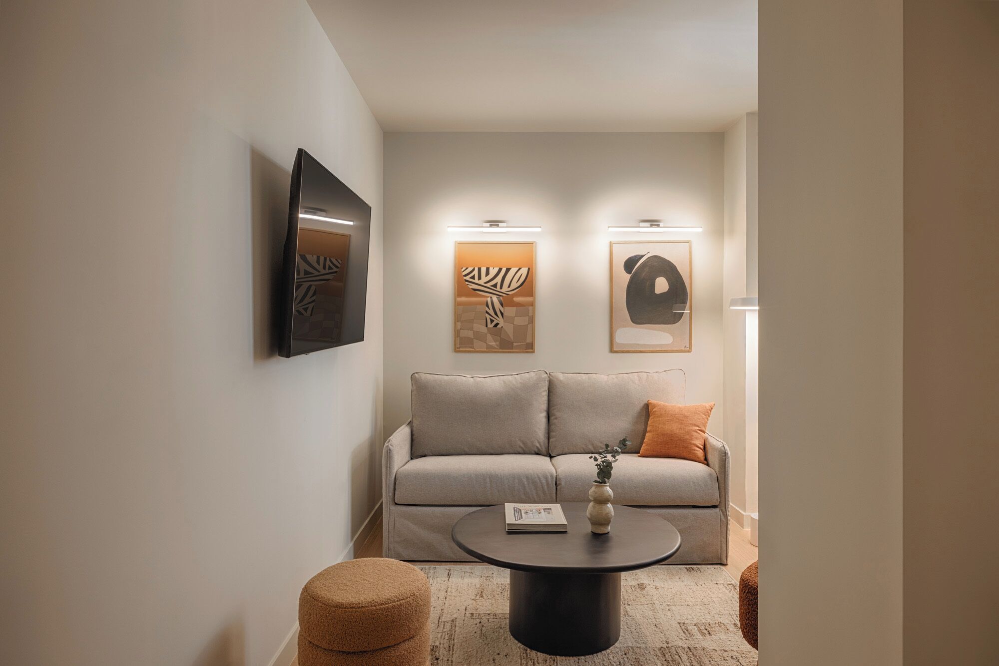 A modern living room with a sofa, a coffee table, and two wall-mounted artworks.