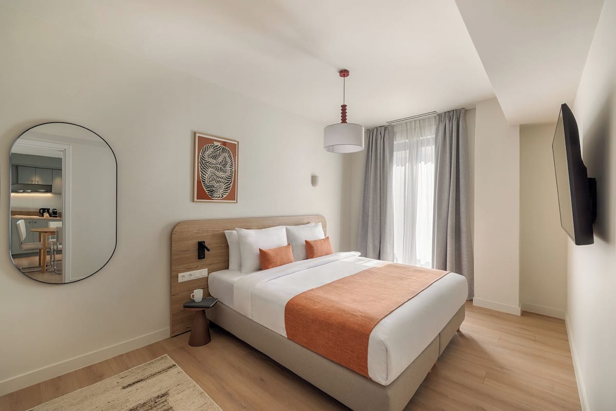 A modern bedroom with a bed, bedside table, and a mirror.