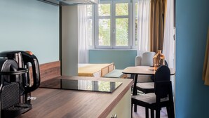 A modern kitchen with a coffee maker, a tablet on the counter, and a view of a dining area with a table and chairs. - Didot by Zoia Living (Athina)