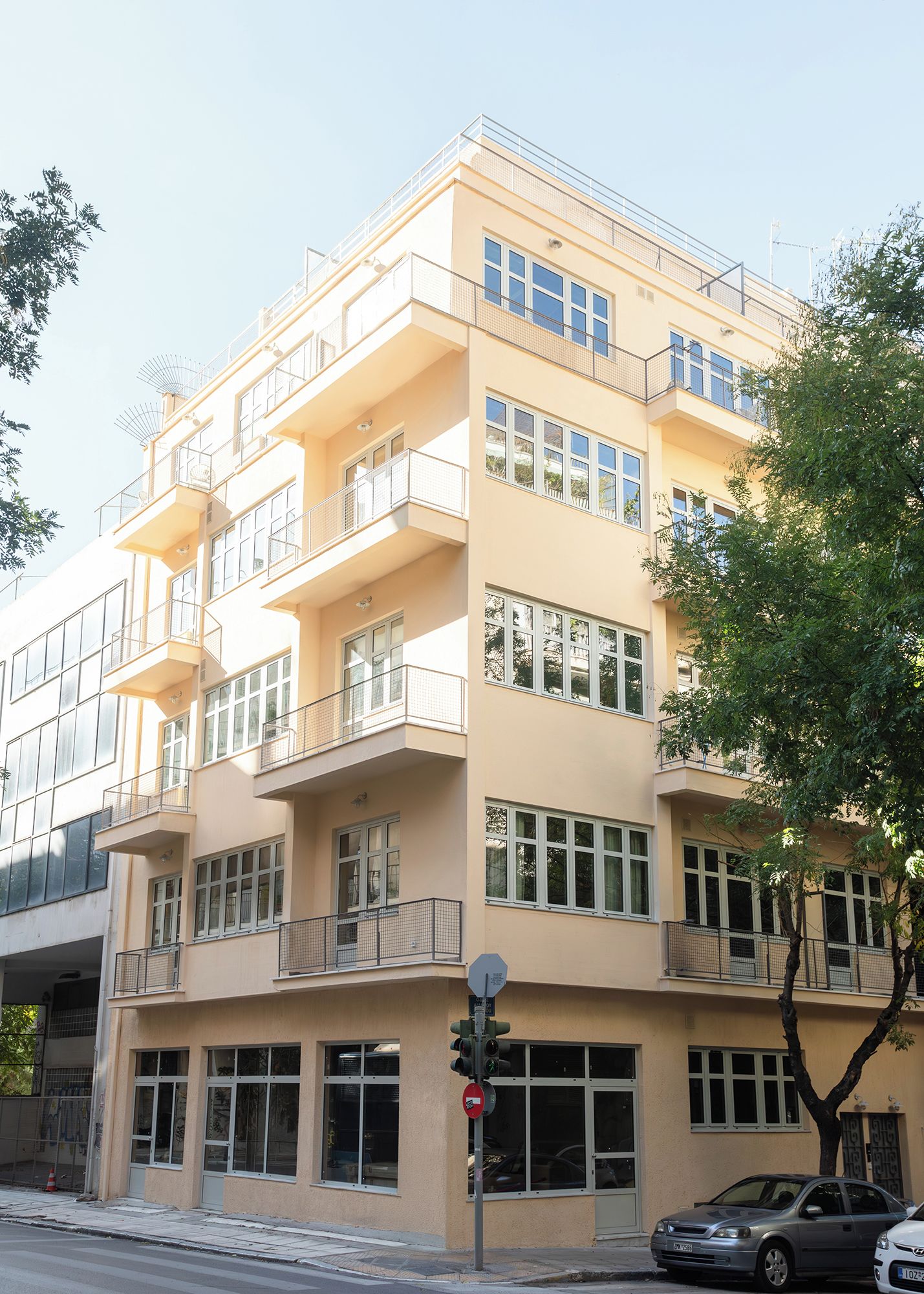 A multi-story residential building with balconies, large windows, and a traffic light.