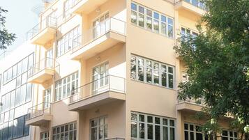 A multi-story residential building with balconies, large windows, and a traffic light.