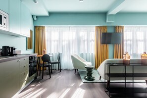 A modern hotel room with a kitchenette, a sofa, a TV, and a bedside table. - Dido by ZOIA Living (Athina)