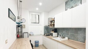 Una cucina compatta con mobili bianchi, un piano di lavoro in legno e un forno a microonde integrato.