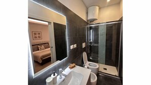 Un bagno moderno con uno specchio grande, una vasca, un water e una doccia.