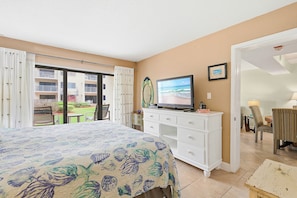 A hotel room with a bed, a TV, a dresser, and a balcony with a view of the sea. - ✨Ocean and Pool Views | 1st Floor with Private Patio | Castle Reef 109✨ (New Smyrna Beach)