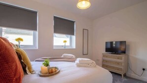 Une chambre d’hôtel avec un grand lit, une télévision et une petite armoire.