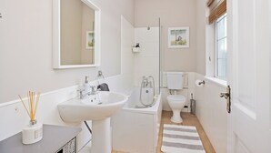 A compact bathroom with a sink, toilet, and shower.
