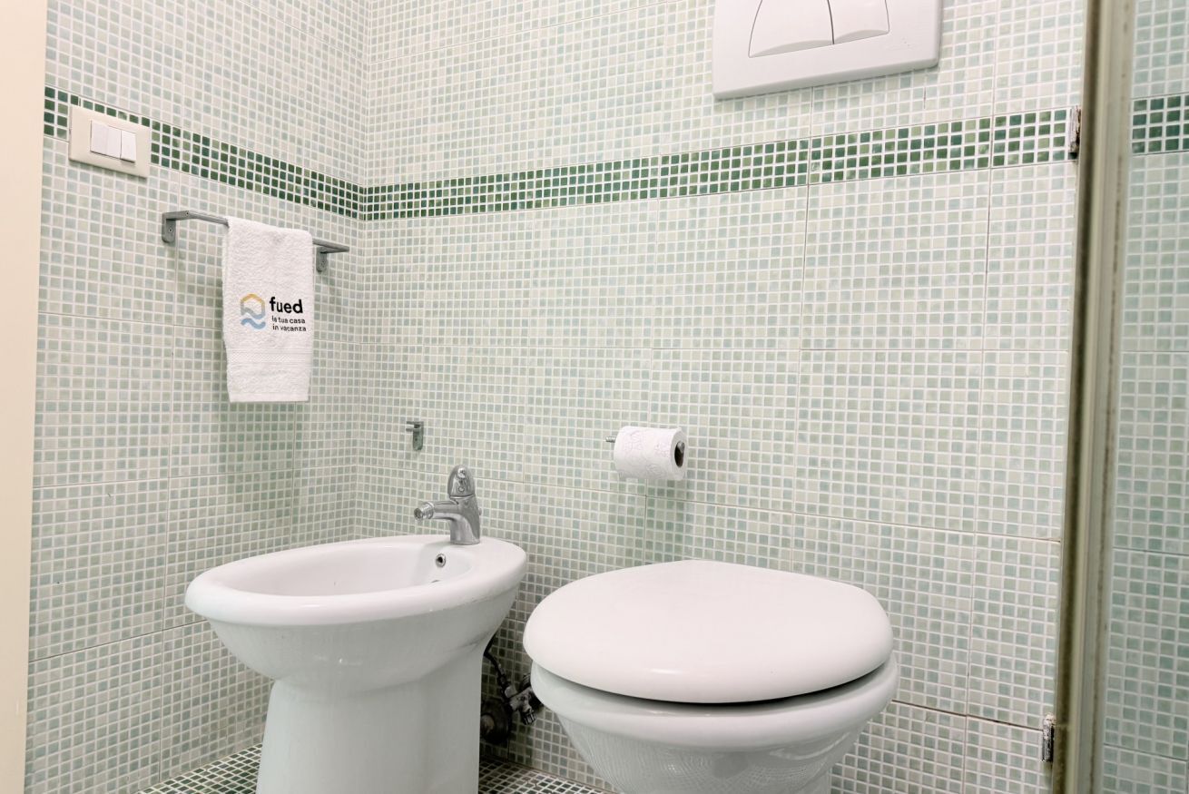 A bathroom with a sink, toilet, and a towel hanging on the wall.