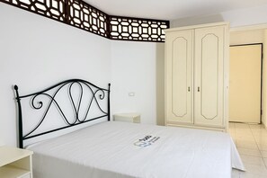 Un dormitorio con cama, armario, mesita de noche y un separador decorativo.