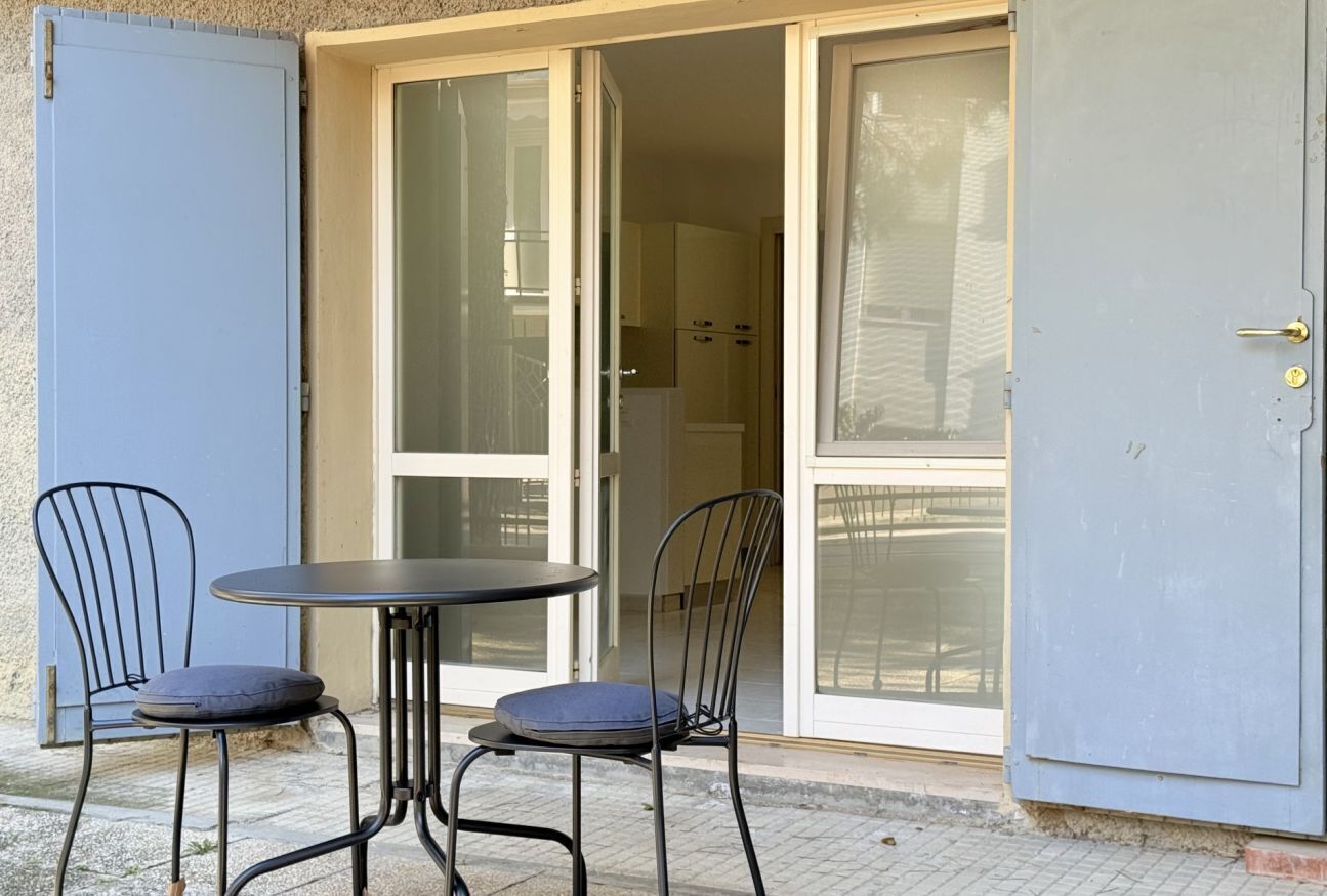 A room with a sliding glass door, a round table, two chairs, and a door with a lock.