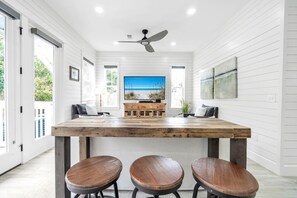 Une cuisine moderne avec un îlot central en bois, des tabourets de bar et une grande fenêtre donnant sur la plage.