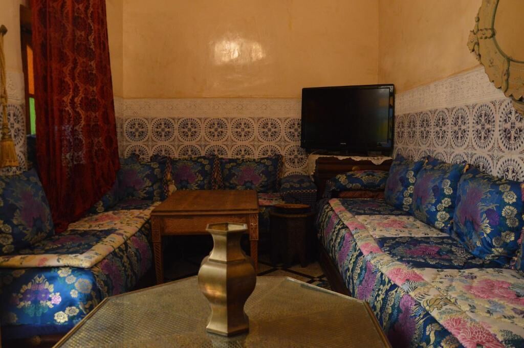 Quarto com sofá, televisão e um vaso decorativo.