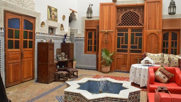 A traditional Moroccan interior with a fountain, wooden doors, and patterned tiles. - Riad oumkaltoum (Fès)