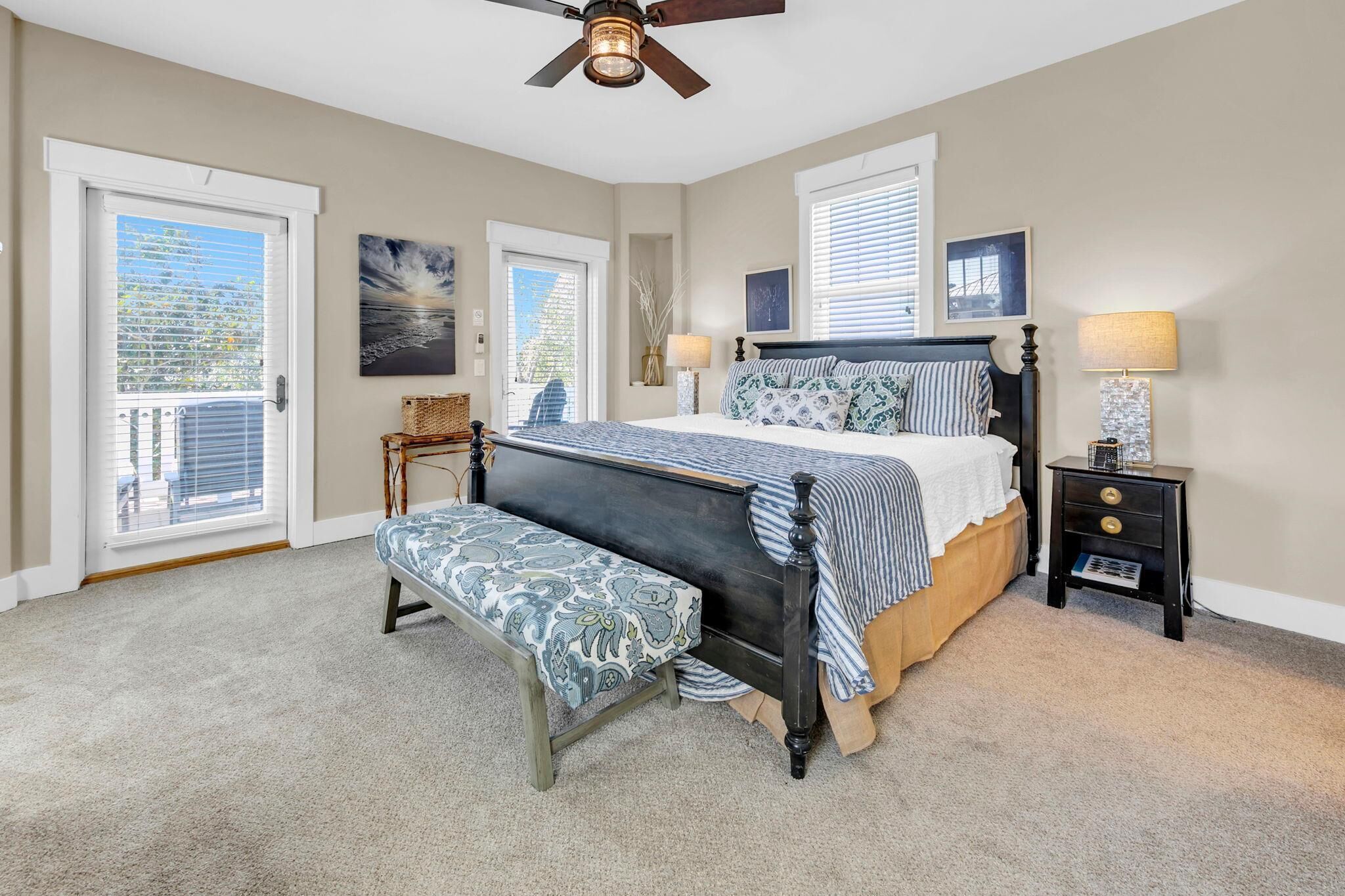 A bedroom with a bed, bench, nightstand, and ceiling fan.