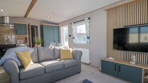 A modern living room with a grey sofa, a flat-screen TV, and a wooden cabinet. - South Beach Landings 0028 (Rye)