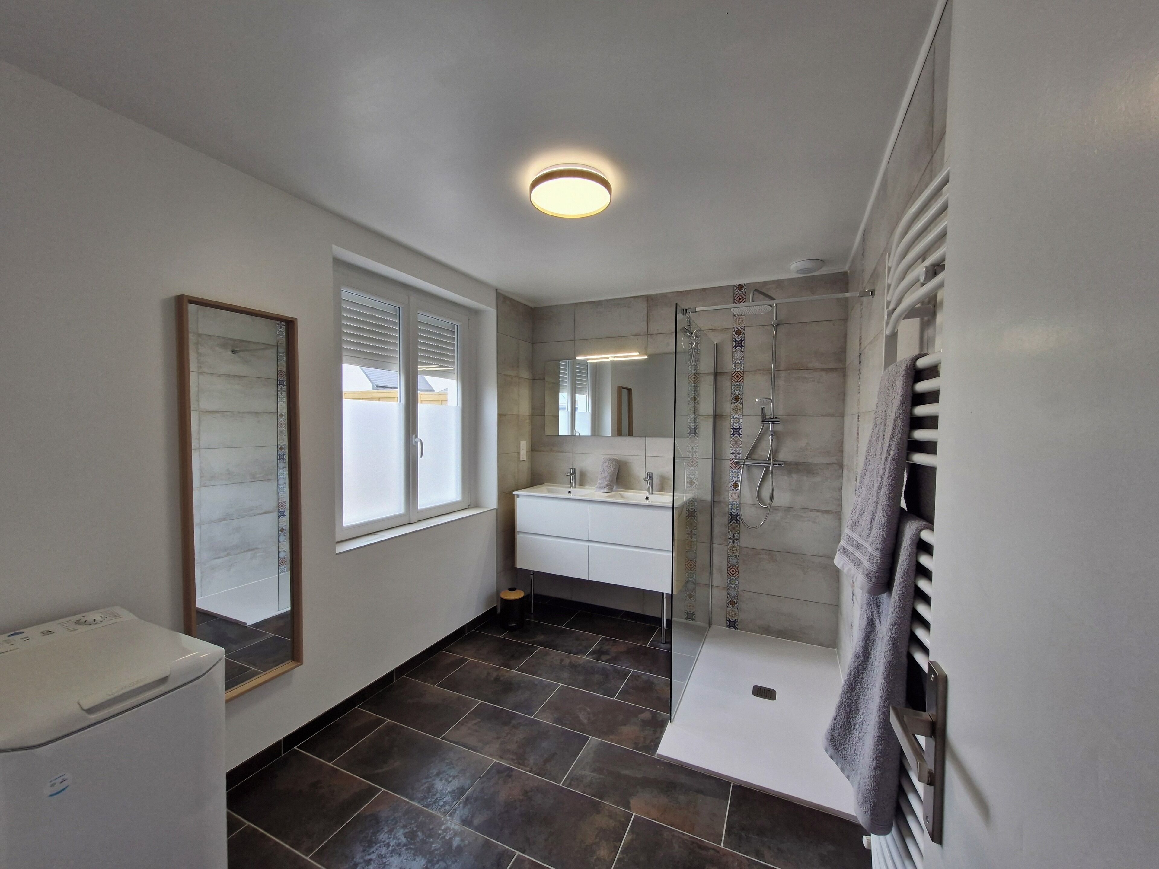 A modern bathroom with a glass shower enclosure, a white sink vanity, and a large mirror.