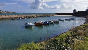 Un port où sont amarrés plusieurs bateaux, un phare et une côte rocheuse.
