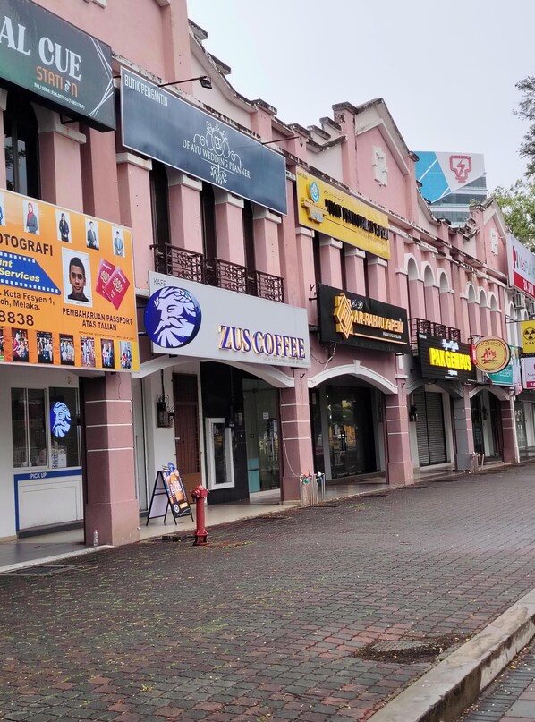 A street with various shops, including a wedding planner, a coffee shop, and a pharmacy. - Ayla Hostel at MITC (Ayer Keroh)
