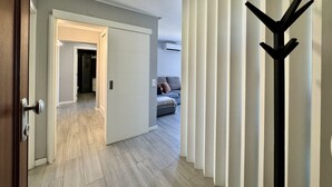 Un pasillo con una puerta que da a una habitación, un perchero y una cama con almohadas.