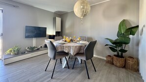 En spiseplads med et rundt bord, stole, en lysekrone og en stor plante.