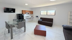 Una sala de estar moderna con una mesa de comedor de cristal, un sofá y un otomano rojo.
