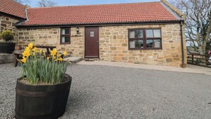 A stone building with a red-tiled roof, a wooden door, and a window with a dark frame. - The Calf House (Saltburn-by-the-Sea)