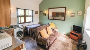 A compact living space with a kitchenette, a dining area, a sofa, a television, and a large mirror. - The Calf House (Saltburn-by-the-Sea)