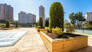 A rooftop garden with neatly trimmed hedges and a paved walkway.