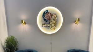 Una stanza moderna con due poltrone blu, un’opera d’arte a parete circolare e due lampade a parete.