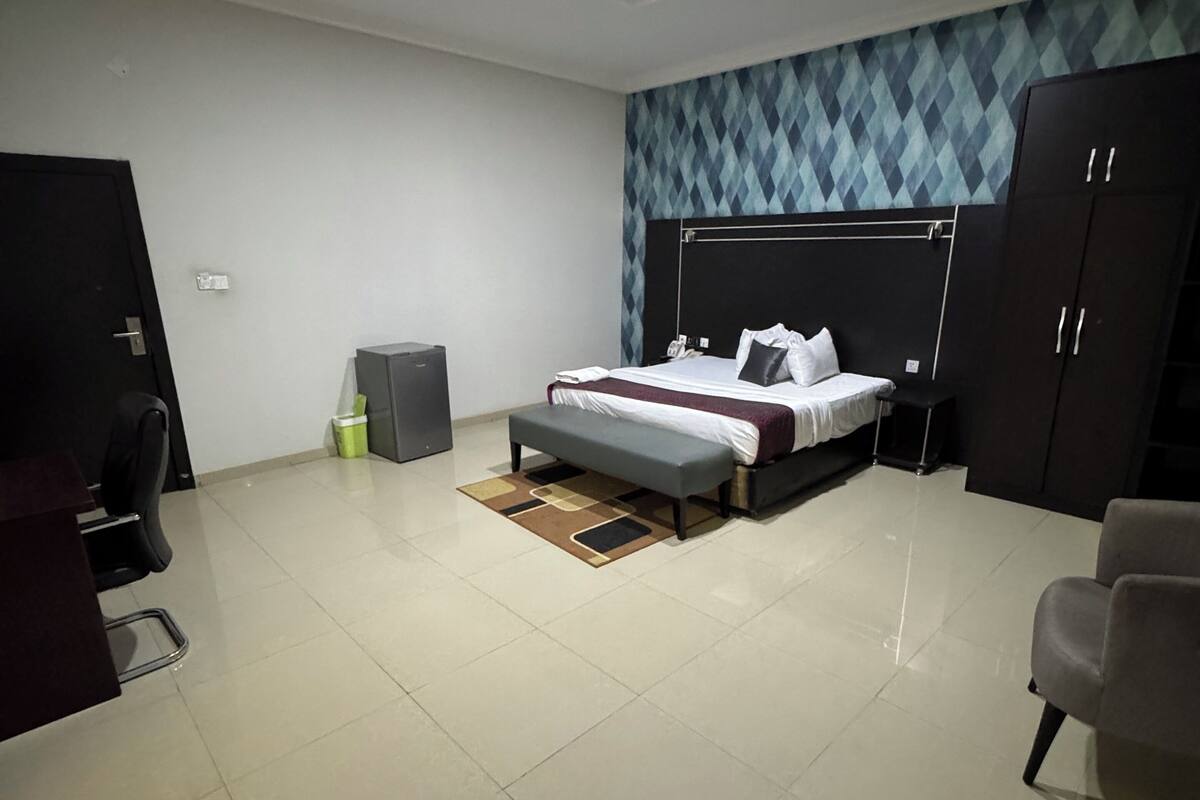 Een moderne hotelkamer met een groot bed, een bureau en een kledingkast.