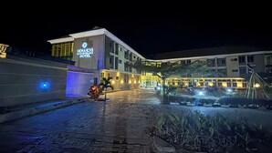 L'ingresso di un hotel con un vialetto lastricato, un edificio ben illuminato e un'area di parcheggio.