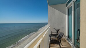 Varanda com vista para o oceano, uma cadeira e uma mesa.