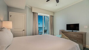 Quarto de hotel com cama, televisão, cômoda e varanda com vista.