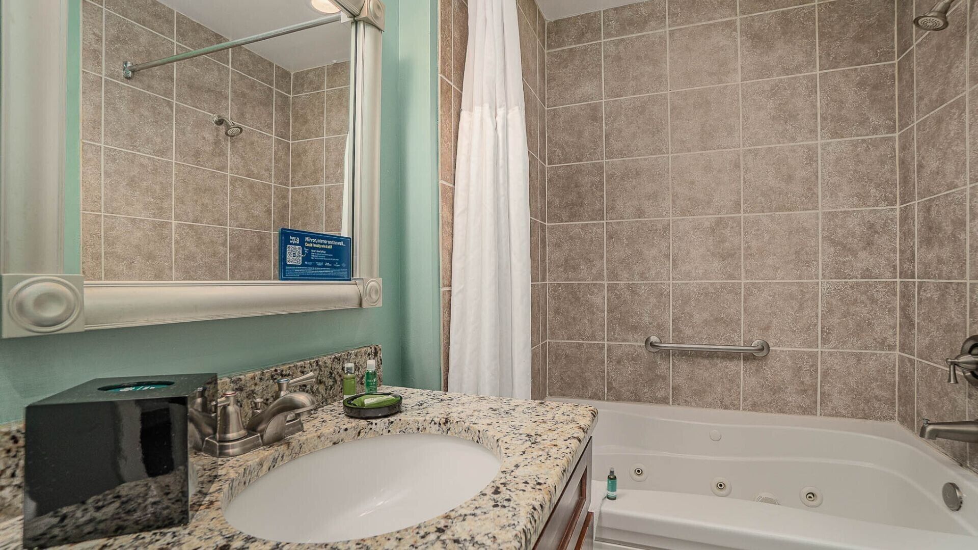 A bathroom with a sink, mirror, shower, and bathtub.
