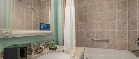 A bathroom with a sink, mirror, shower, and bathtub.
