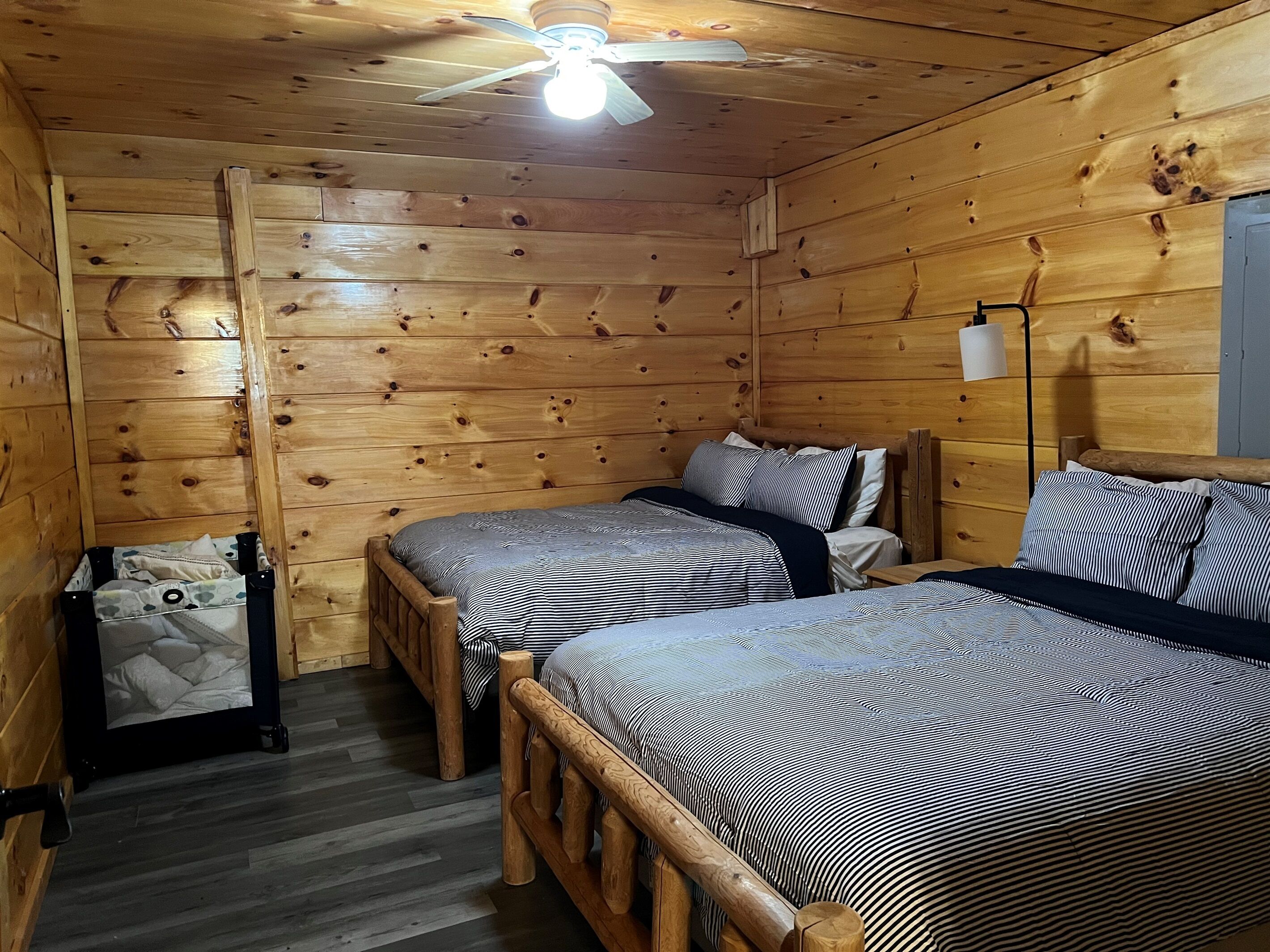 A cabin-style room with two wooden beds, a ceiling fan, and a small table.