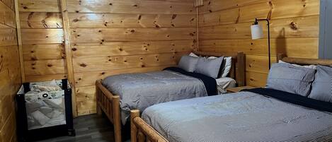 Una habitación tipo cabaña con dos camas de madera, un ventilador de techo y una pequeña mesa.