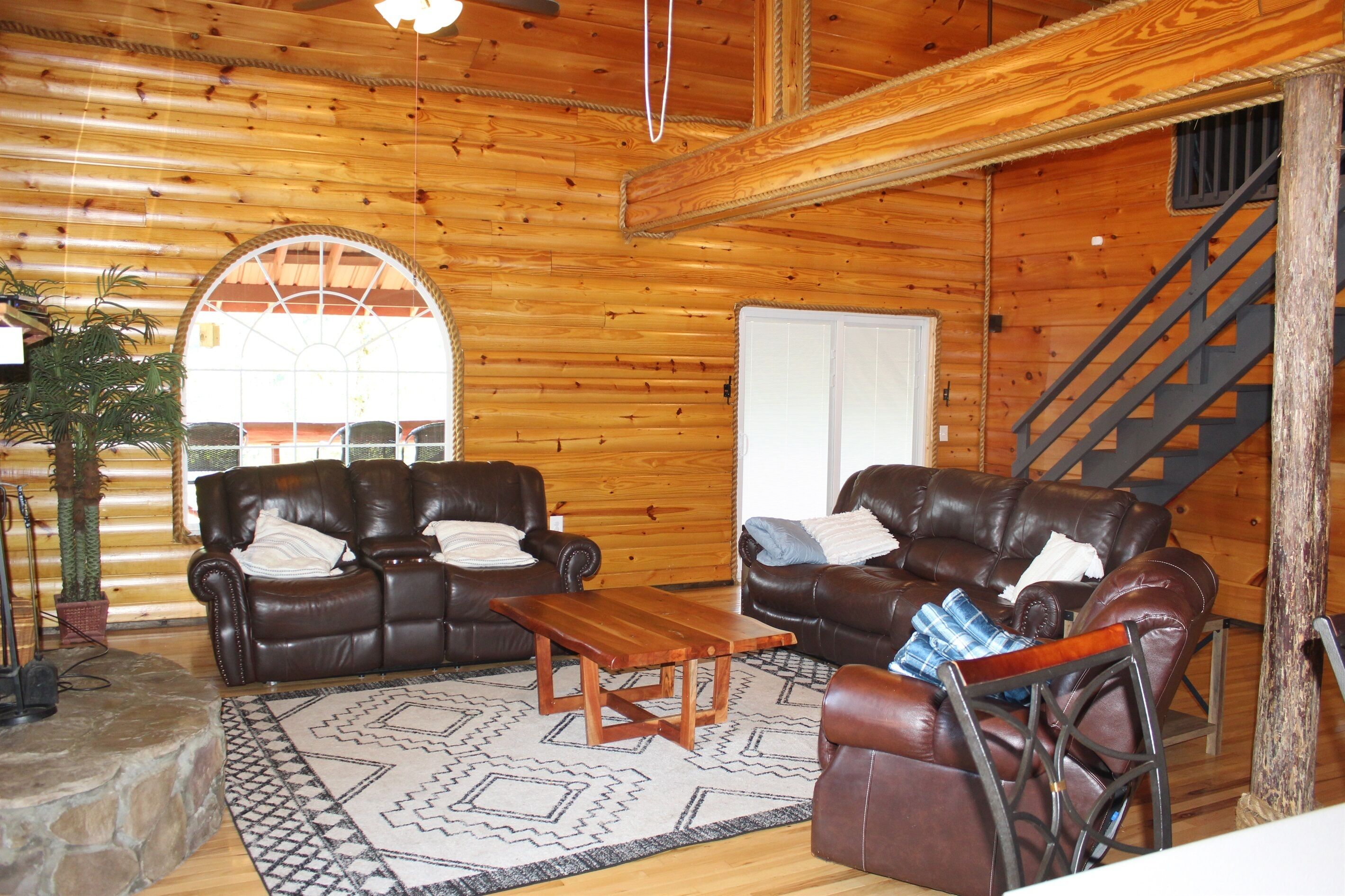 A log cabin interior with two leather sofas, a wooden coffee table, and a patterned rug.