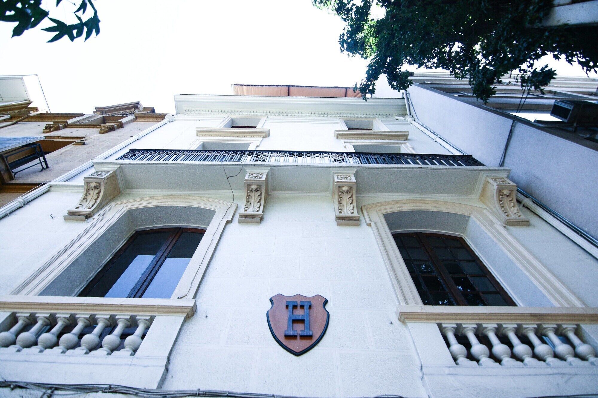 Fachada de edificio con dos ventanas simétricas, un emblema en forma de escudo central y molduras decorativas.