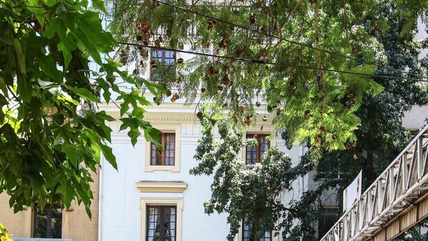 A building with a white facade, a balcony, and a sign indicating a food service. - Hotel Vista Hill (Santiago)