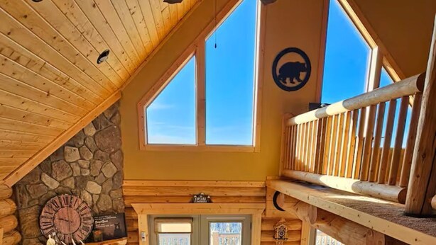 A cozy log cabin interior with a stone fireplace, a large wooden ceiling fan, and a dog bed. - Charming Log Cabin + Mountain Views + Fireplace + Hot Tub + Pet Friendly (Cripple Creek)