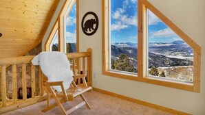 A room with a wooden bench, a fluffy white throw, and a bear silhouette on the wall. - Charming Log Cabin + Mountain Views + Fireplace + Hot Tub + Pet Friendly (Cripple Creek)