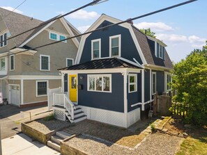 A two-story house with a front porch, a garage, and a well-maintained lawn. - State St. Parlor | Walk Downtown | Newly Designed (Portsmouth)