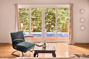 Une pièce dotée d’une porte-fenêtre coulissante donnant sur une piscine, d’une chaise bleue et d’une petite table.