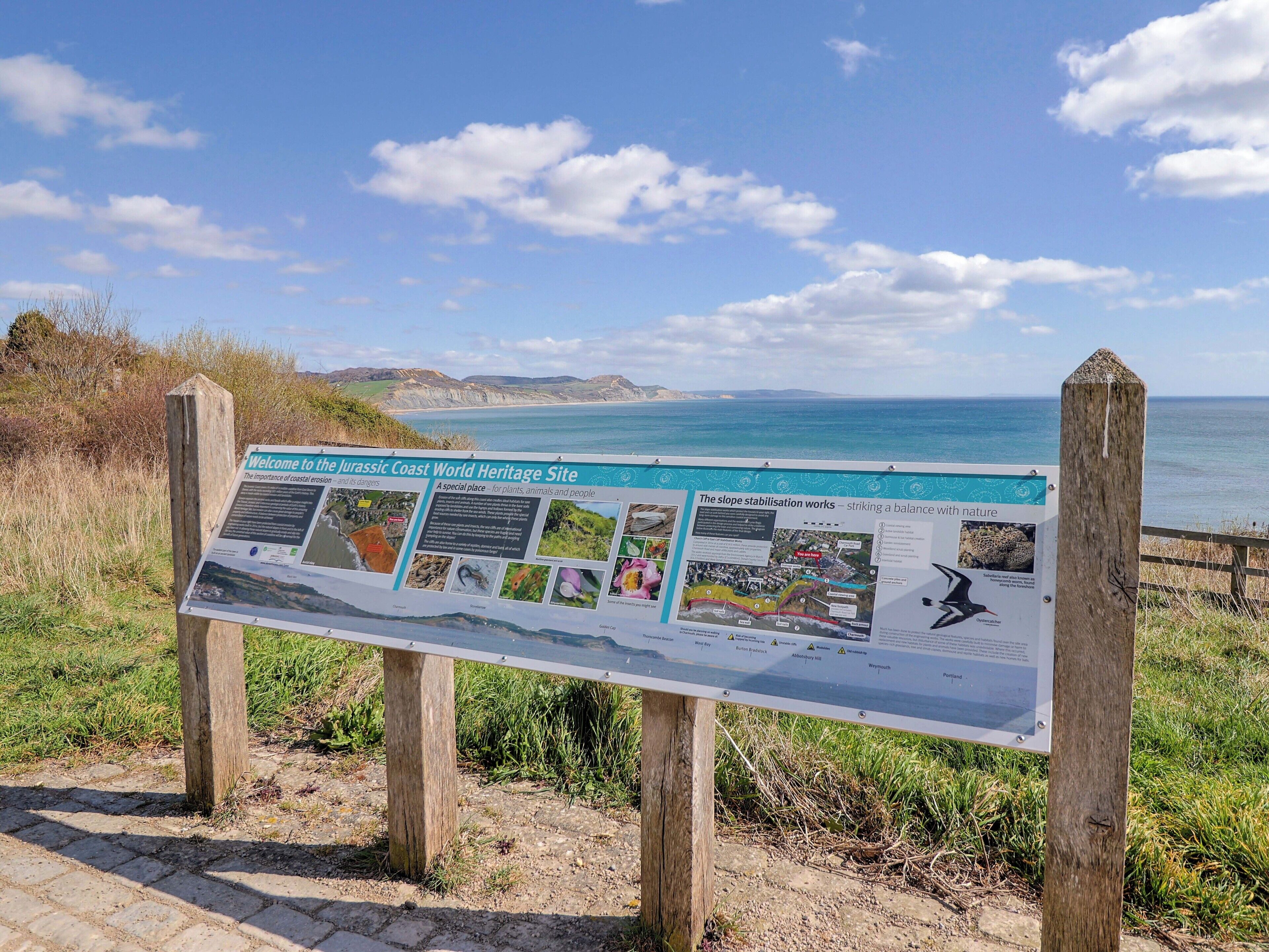 A wooden signpost with information about the Jurassic Coast World Heritage Site.