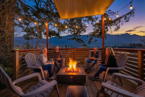 Una terraza con pozo de fuego, sillas y vistas a las montañas.