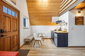 Una cocina moderna con techo de madera, comedor con banco y vistas al exterior a través de una ventana.