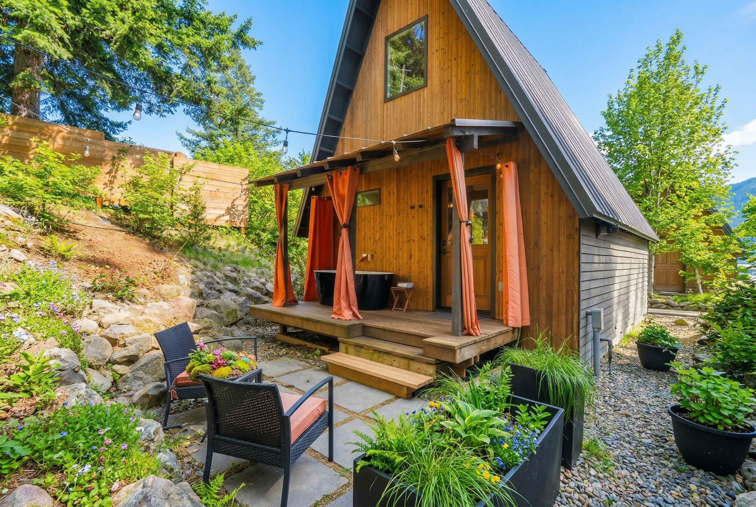 Eine Holzhütte mit Veranda, Sitzgelegenheiten im Freien und Blumentöpfen.