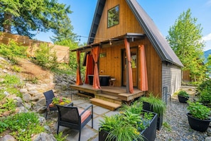 Eine Holzhütte mit Veranda, Sitzgelegenheiten im Freien und Blumentöpfen.