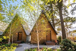 Une cabane en bois avec un toit en pente, une véranda à l’avant et un petit jardin.